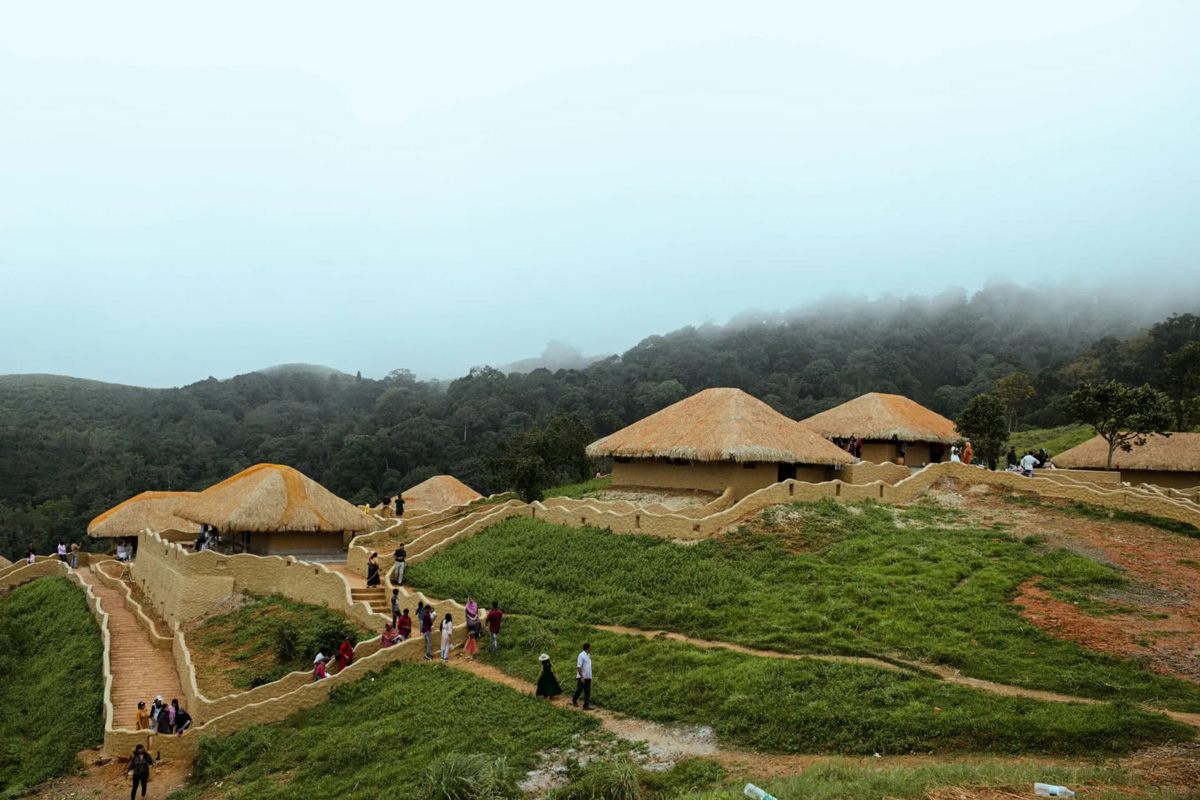 Travellers standing above a sea of clouds on a hilltop viewpoint in Wayanad, Kerala